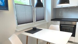 A modern kitchen with white cabinetry, a black countertop, and a built-in oven. - Apartment Schloofschdubb in Fuldatal Nähe Kassel (Fuldatal)