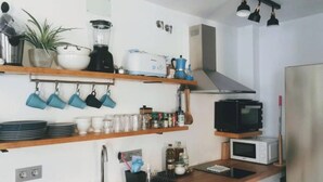 Une cuisine moderne avec des étagères en bois, un évier, un réfrigérateur, un four à micro-ondes et un mixeur.