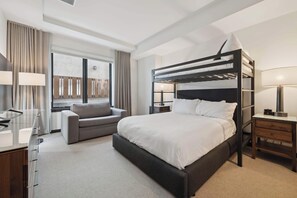 Relax in a cozy space with a bunk bed, sofa, and desk, offering a comfortable retreat with a view.