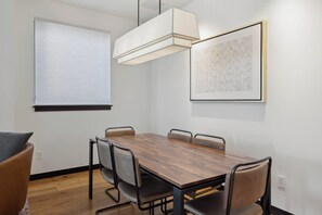 Conference room with a wooden table and six chairs, featuring a large window and a pendant light.
