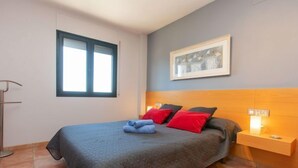 A bedroom with a bed, a nightstand, a window, and a framed picture on the wall. - Ullastreta by Interhome (La Bisbal D'Emporda)