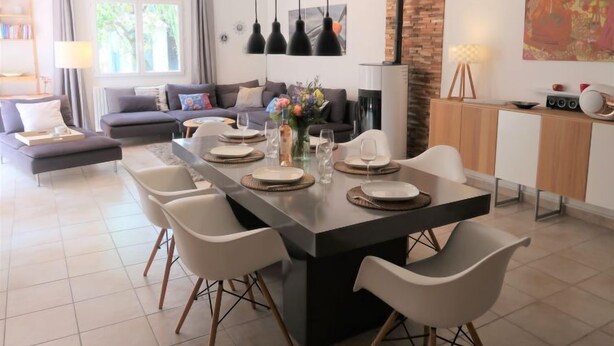 Un soggiorno moderno con zona pranzo, che include un divano, un tavolino e un tavolo da pranzo apparecchiato per quattro persone.