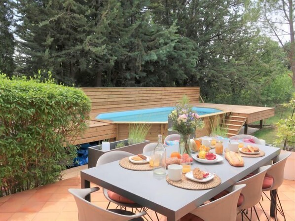 Une table à manger installée à l’extérieur, avec une piscine en arrière-plan.