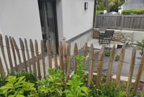 Een omheinde achtertuin met een patio, zitplaatsen buiten en een stenen muur.