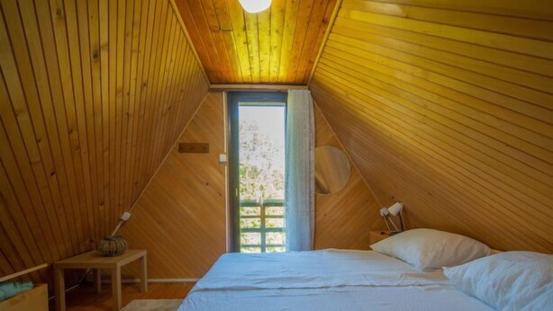 Quarto de sótão aconchegante, paredes de madeira e teto inclinado.