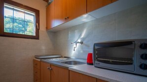 Uma cozinha com armários de madeira, forno embutido, pia e janela com vista para árvores.