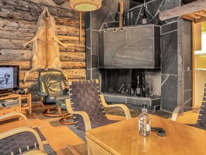 A cozy interior with a stone fireplace, leather seating, and a television.