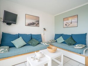 A modern living room with a sofa set, a coffee table, a TV, and artwork on the walls.