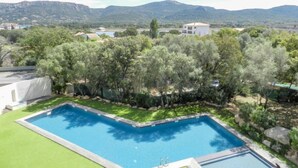 A rectangular swimming pool surrounded by a well-maintained lawn and trees, with a mountainous backdrop. - Résidence Cita Di Sali 12 by Interhome (Porto Vecchio)