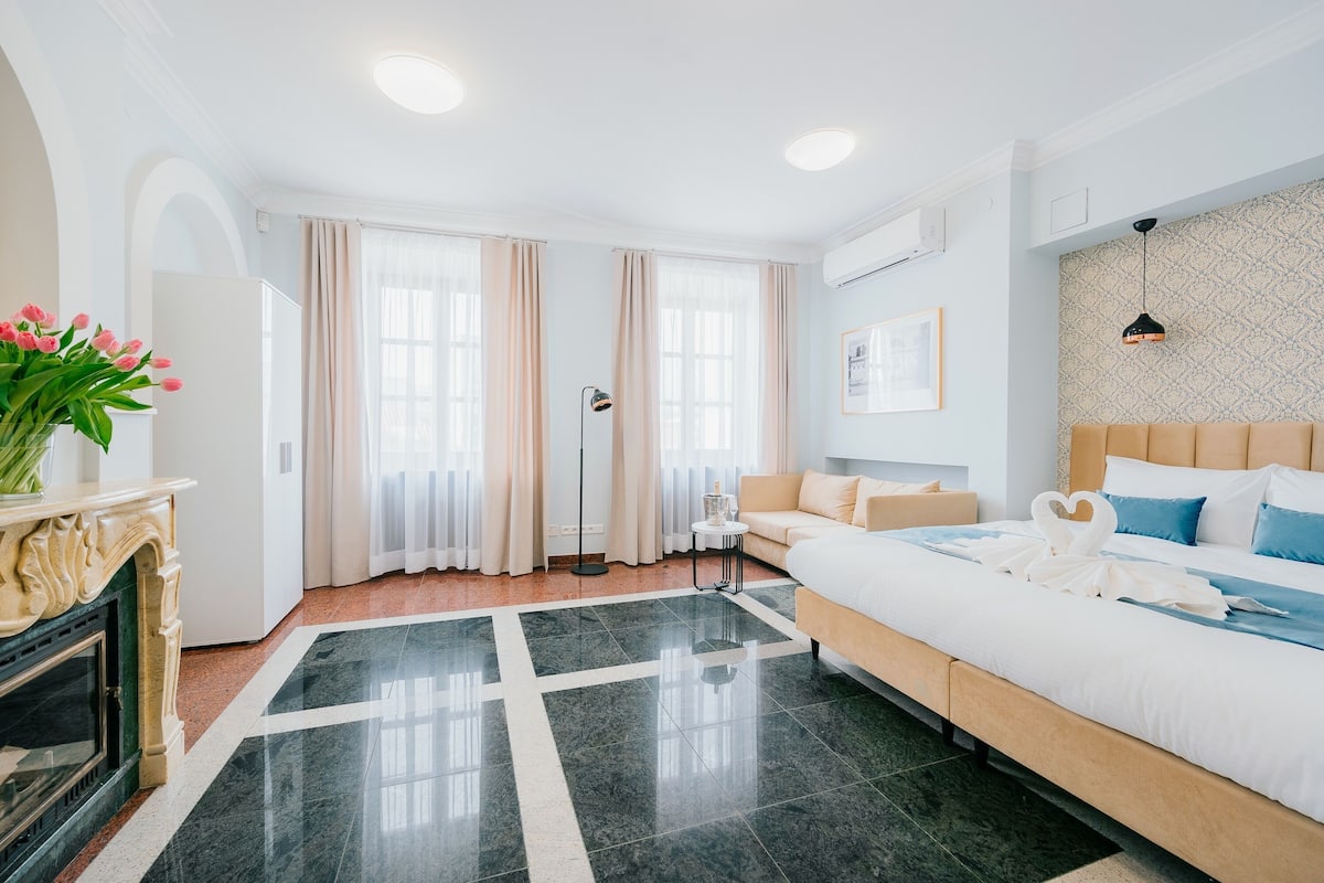 Un hotel moderno con una cama grande, un sofá, una chimenea y vistas a la ciudad.