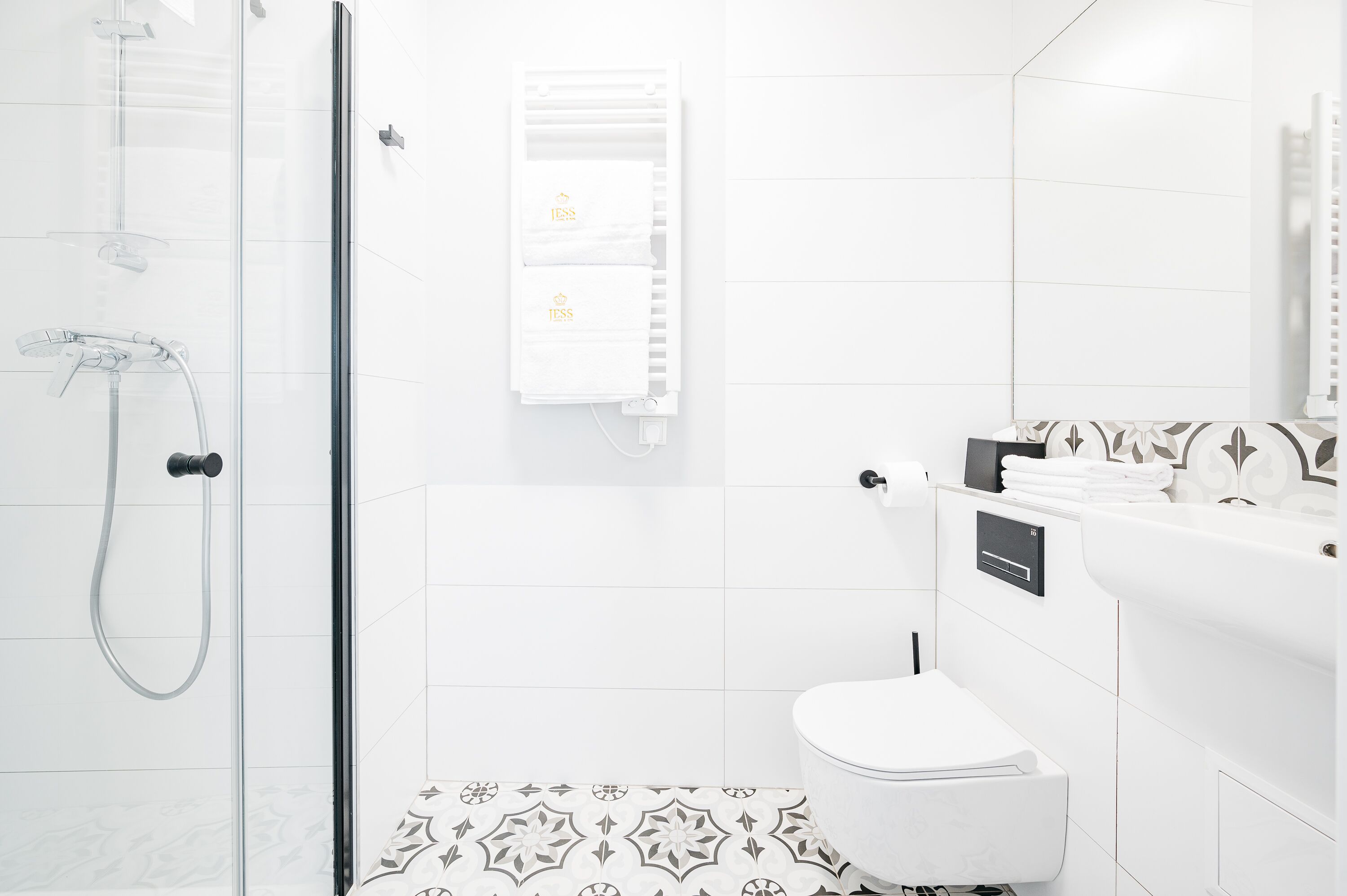 Casa de banho moderna com chuveiro envidraçado, sanita e lavatório com um porta-toalhas.