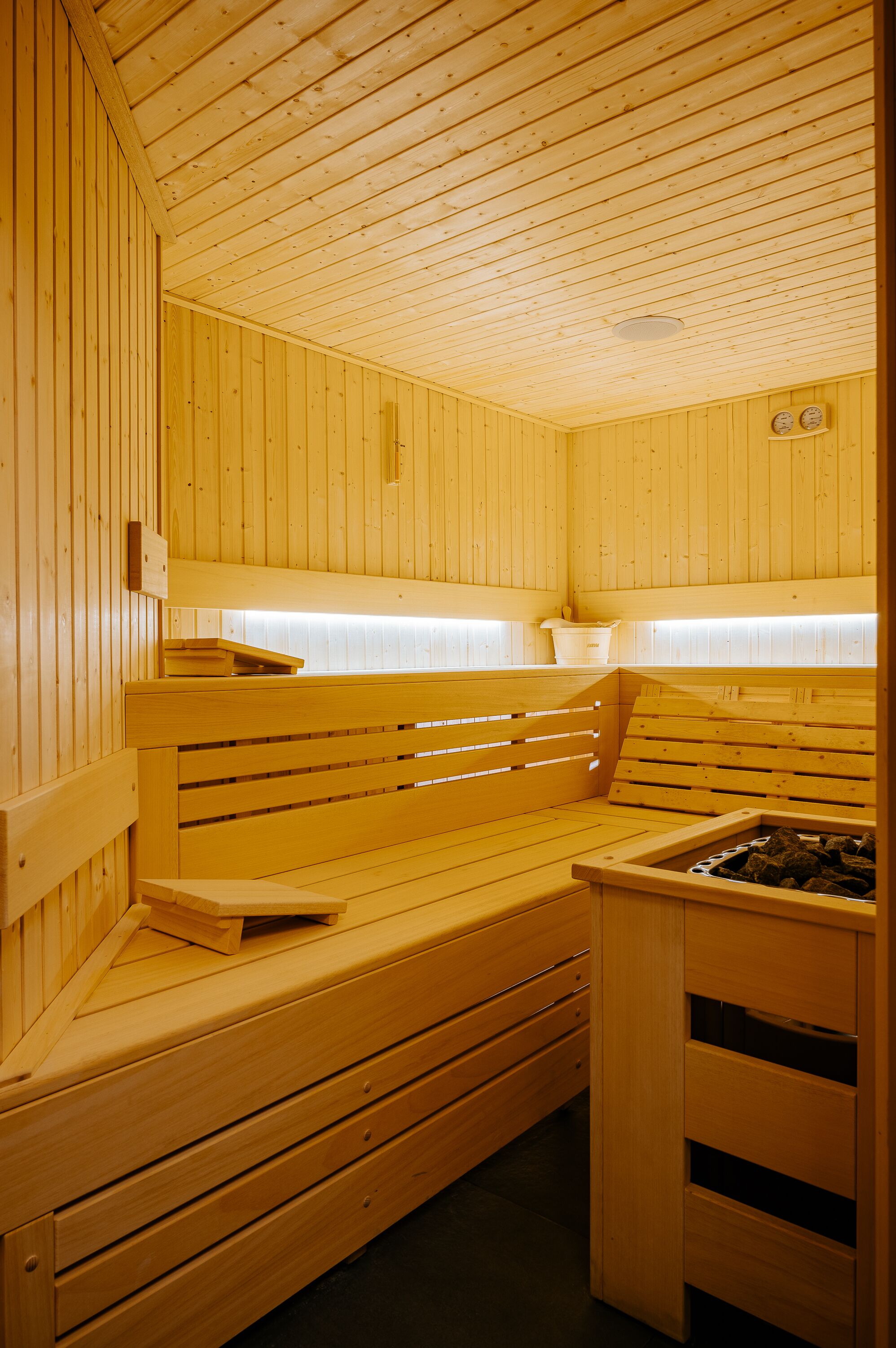 Una sauna de madera con bancos y un asiento de banco, una pared de madera y un pequeño armario de madera.