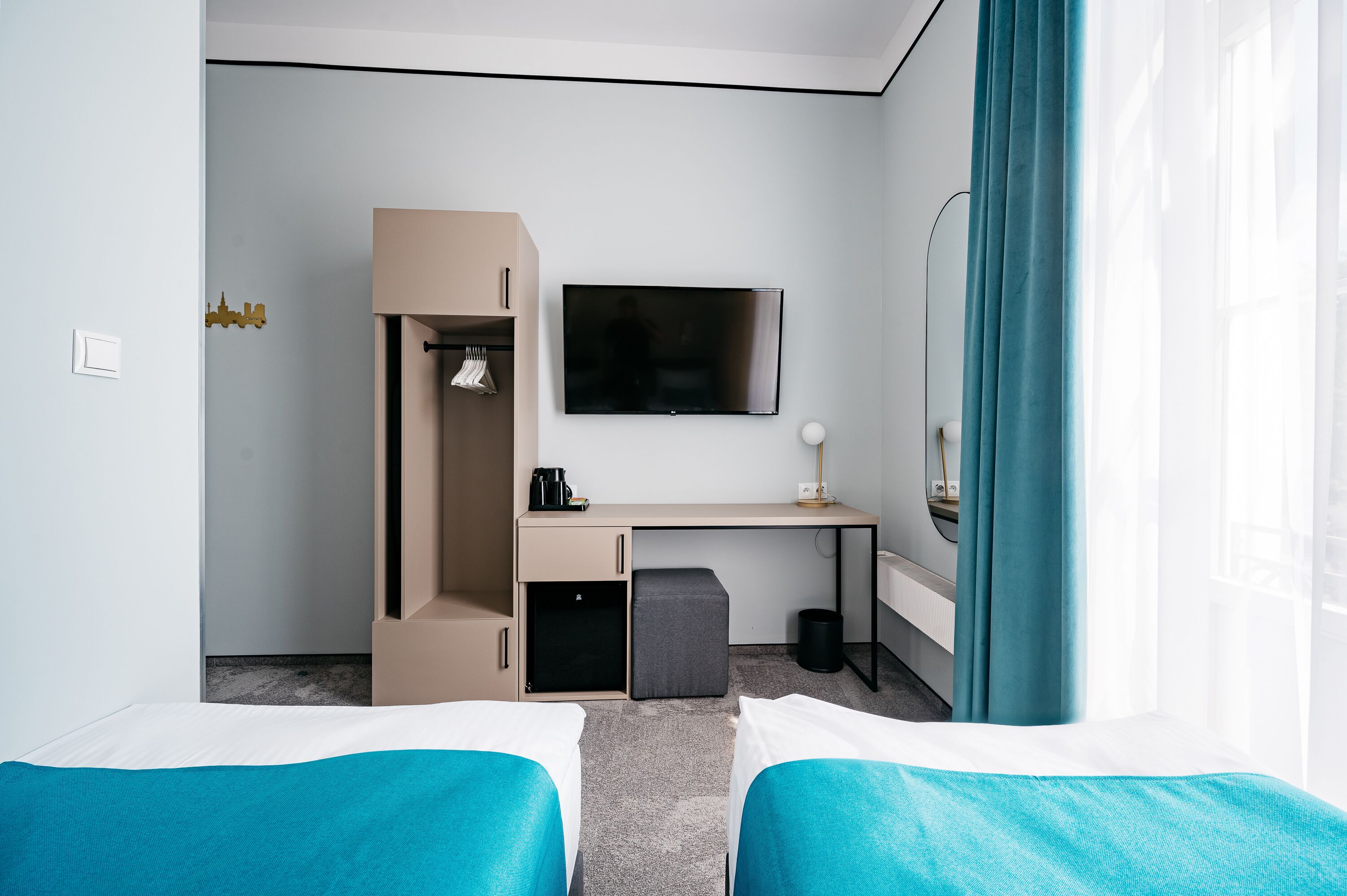 A hotel room with two beds, a desk, a TV, and a wardrobe.