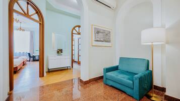 Un hall de hotel con un sofá azul turquesa, una lámpara de pie y un cuadro en la pared.