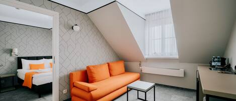 A modern room with a bed, orange sofa, and a small table.
