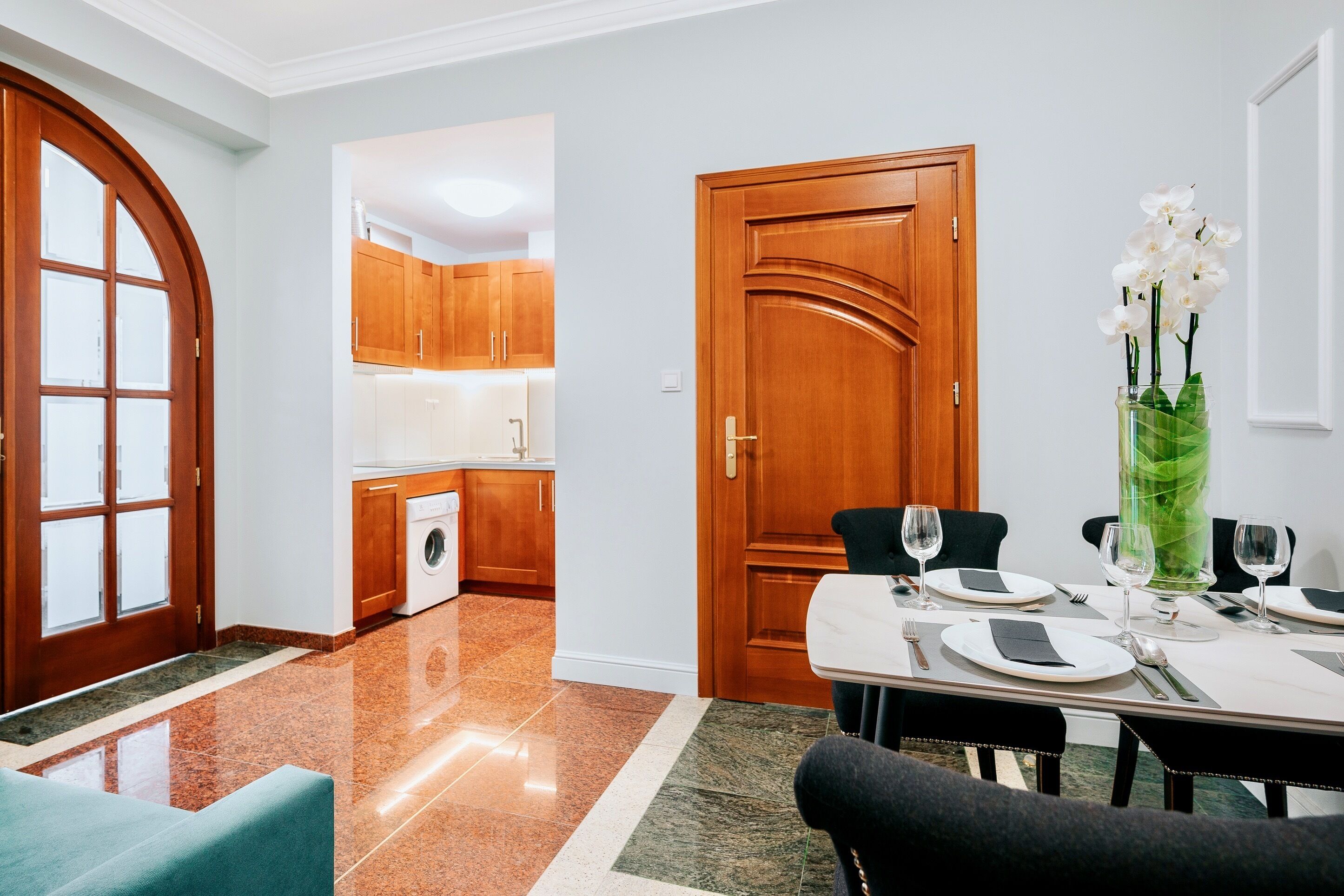 A modern kitchen with wooden cabinets and a dining area with a table set for two.