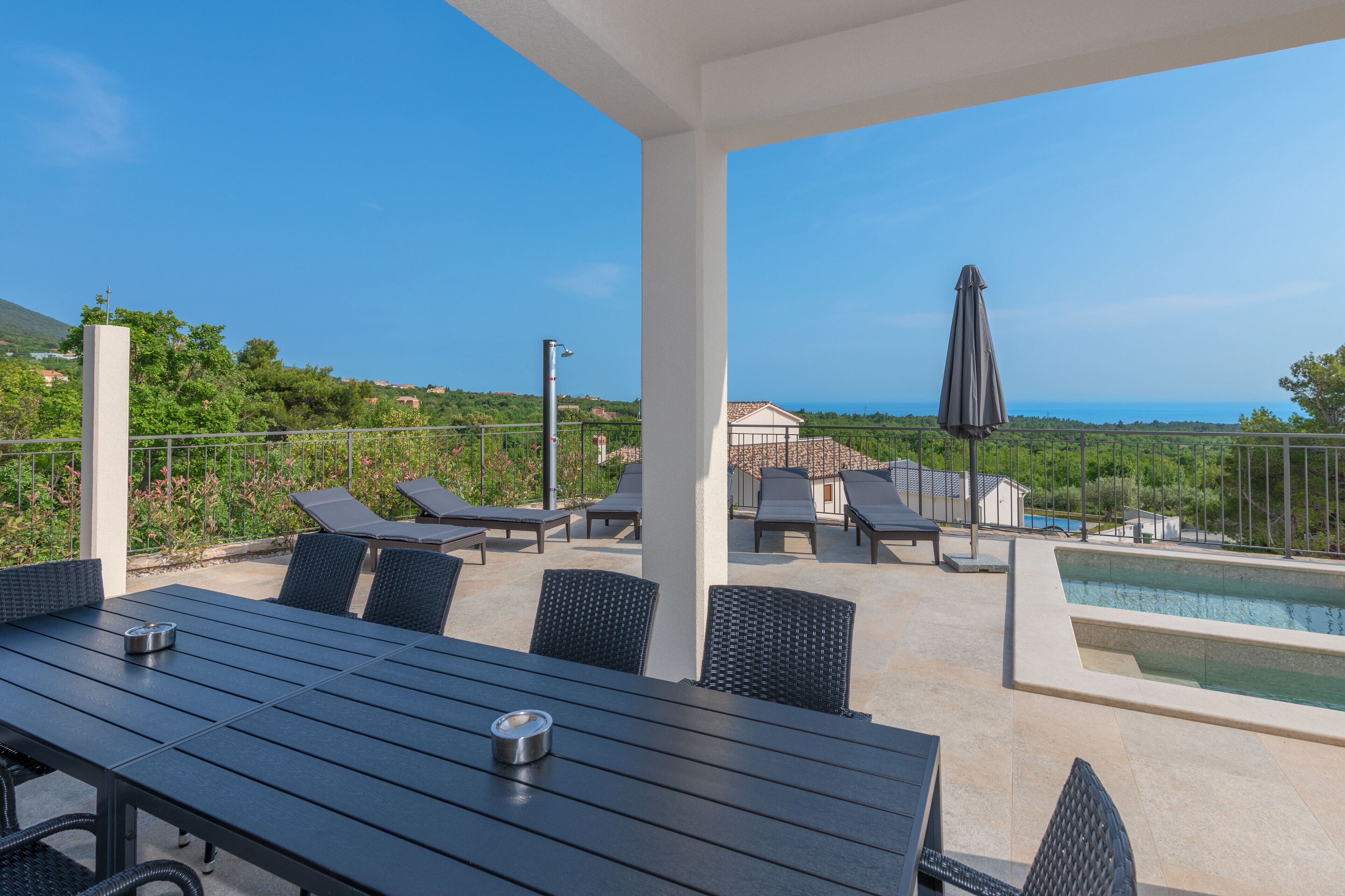 A rooftop terrace with a pool, lounge chairs, and a table.