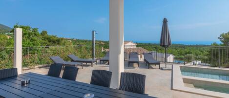 A rooftop terrace with a pool, lounge chairs, and a table.