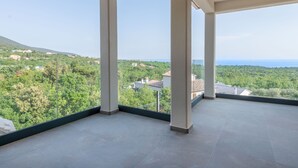 A spacious balcony with a clear view of a green landscape and distant buildings.