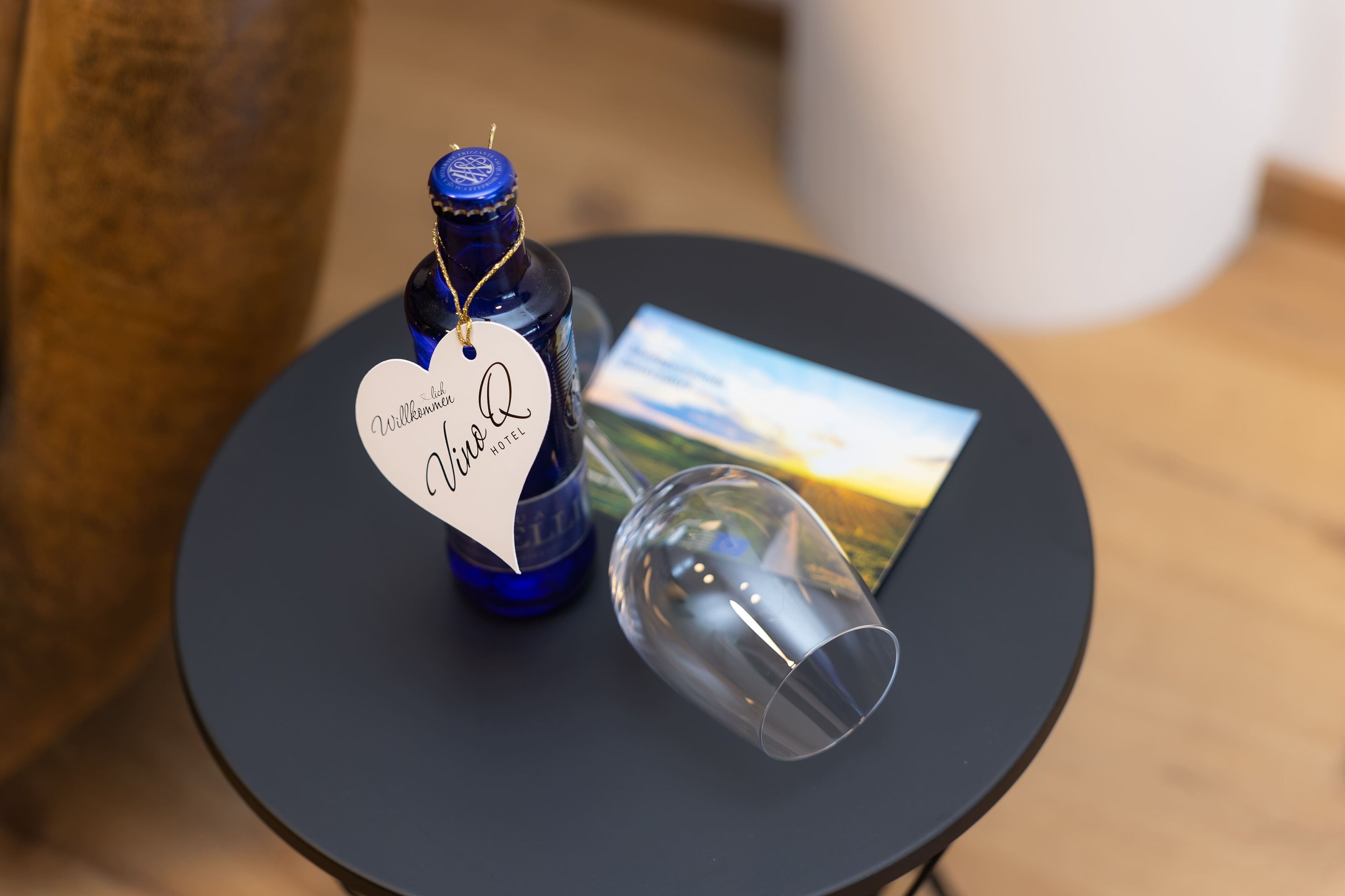 Une bouteille de vin avec une étiquette, un verre à vin et une carte, le tout posé sur une table ronde.