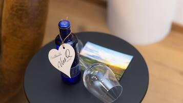 Une bouteille de vin avec une étiquette, un verre à vin et une carte, le tout posé sur une table ronde.