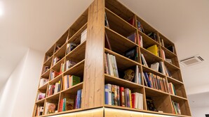 A large wooden bookshelf filled with books. - Self-Check-in Hotel VinoQ Zistersdorf (Zistersdorf)