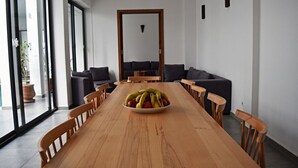 Una sala de conferencias con una larga mesa de madera, varias sillas, un frutero y un sofá.