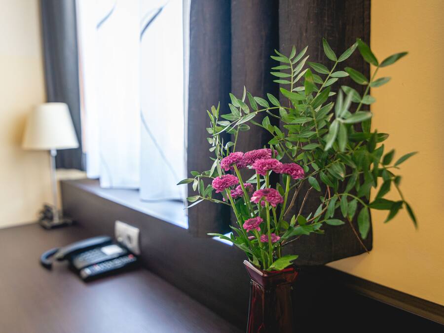 Un escritorio con un jarrón de flores, una lámpara y un teléfono.