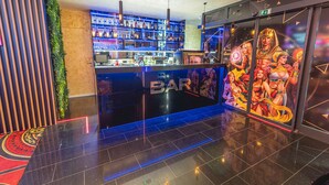 Eine Bar mit einer Theke, Flaschenregalen und einem Wandbild mit ägyptischen Figuren.