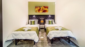 A hotel room with two beds, a large artwork above the headboard, and a nightstand with a lamp.
