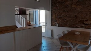 Une cuisine dotée d’un plan de travail en bois, un coin repas avec une table et des chaises, et un mur en pierre.