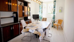 A modern kitchen with a large dining table, built-in wooden cabinets, and a flat-screen TV. - Single-storey house 110m², residential area, 500m from town center (Mirande)