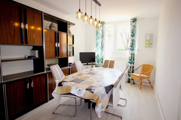 Cozinha moderna com uma grande mesa de jantar, armários de madeira embutidos e uma TV de tela plana.