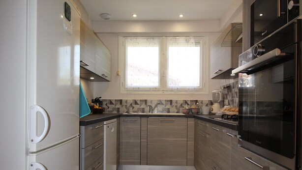 A modern kitchen with stainless steel appliances, a window above the sink, and light wood flooring. - Single-storey house 110m², residential area, 500m from town center (Mirande)