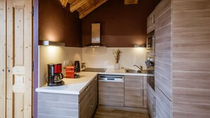 Eine moderne Küche mit Holzausstattung, einer weißen Arbeitsplatte, einem eingebauten Ofen und einem Edelstahl-Spülbecken.