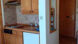 A compact kitchen with wooden cabinets, a built-in dishwasher, and a small countertop. - East-facing studio cabin for 4 guests, pet-friendly (Valloire)