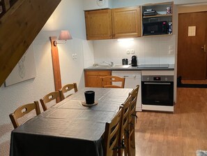 A compact kitchen with wooden cabinets, a microwave, a coffee maker, and a dishwasher. - Chalet 3 Rooms, 8 Pers., Terrace, Free Parking (La Joue du Loup)