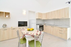 Een koelkast, een oven, een kookplaat, kookgerei, borden en bestek
