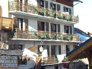 Ein mehrgeschossiges Gebäude mit mit Grünwerk geschmückten Balkonen.