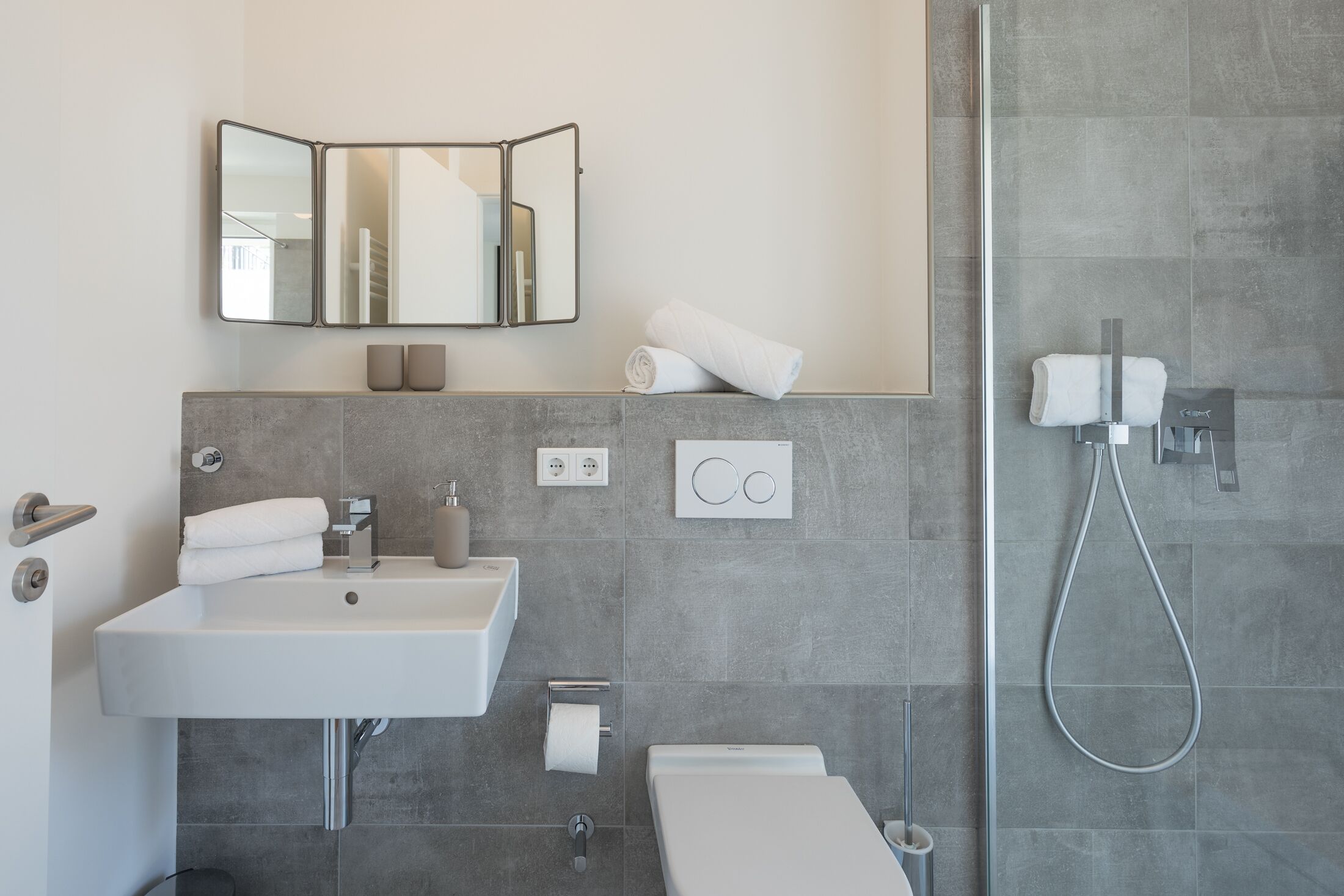 Ein modernes Badezimmer mit einem großen Waschbecken, einem Spiegel, einer Toilette und einer Dusche.
