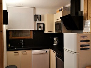 A compact kitchen with a Bosch dishwasher, a microwave, and a refrigerator. There are framed pictures on the wall and a small potted plant on the counter. - Duplex chalet 3 rooms, 6 pers, Superdevoluy station (Le Dévoluy)