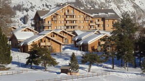 A large wooden lodge with multiple balconies and a mountain backdrop. - 3-room chalet, terrace, games, near slopes (Le Dévoluy)