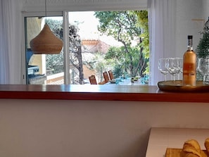Un comedor con vistas a un jardín, una botella de vino y una bandeja con copas.