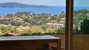 A balcony with a view of a coastal town, including buildings and a distant island. - Villa with heated pool and panoramic views of the Gulf of Saint Tropez (Cavalaire-sur-Mer)