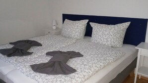 Uma cama com colcha florida, duas almofadas e um cobertor escuro.