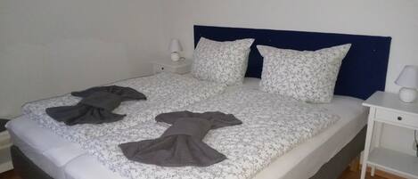 Una cama con una colcha estampada, dos almohadas y una manta oscura.