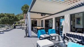 Ein Terrassenbereich im Freien mit Sitzgelegenheiten, einer Statue und einem Restaurant namens 'Culinaire' im Hintergrund.