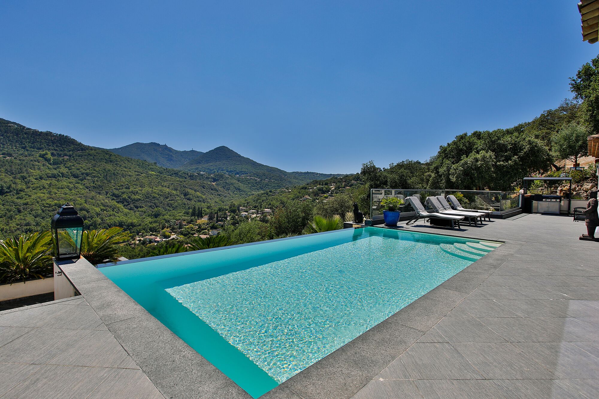 A swimming pool with a view of mountains, lounge chairs, and a stone pathway.