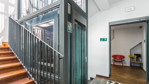 A staircase with a metal railing, a glass elevator door, and a checkered floor pattern. - Dada Premium Aparthotel (Kraków)