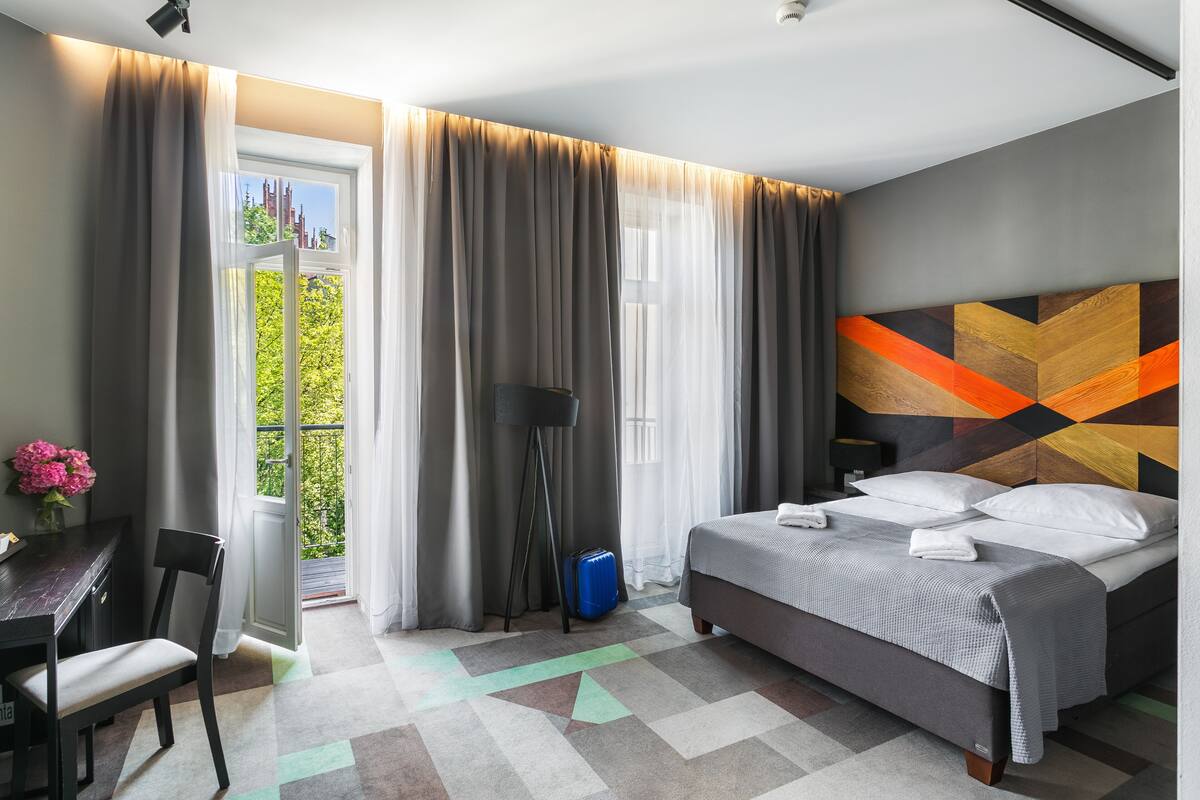 A hotel room with a bed, a desk, and a chair.